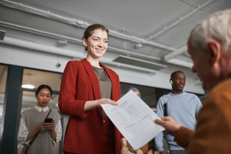 Job seeker handing her resume to an employer at a career fair